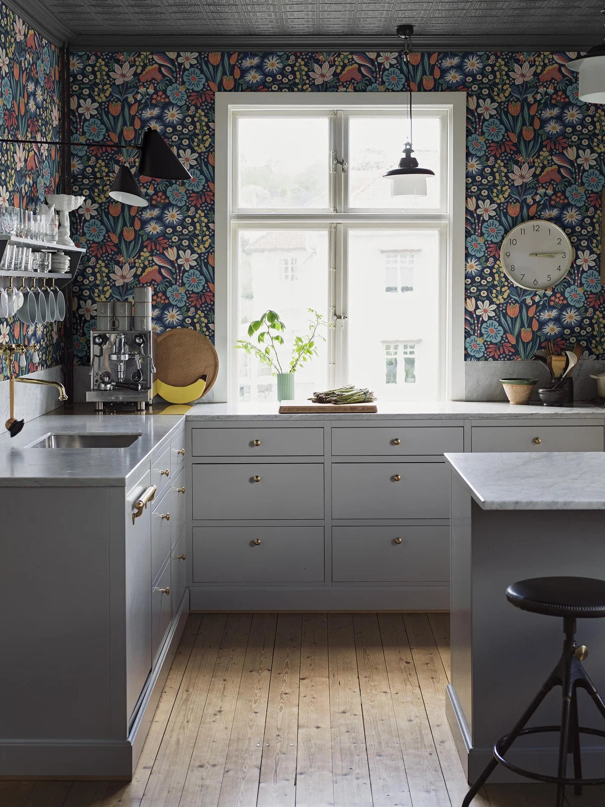 Colored in cheerful tones of green, turquoise, yellow, red and white on a deep dark blue background, our Trädgården wallpaper in a surface print brings a garden scene to life on your walls.