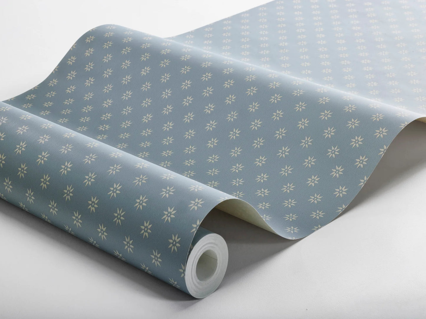 Colored in the cool hues of dawn, our Skogsstjärna wallpaper features linen-colored stars set against a soft dove blue background.