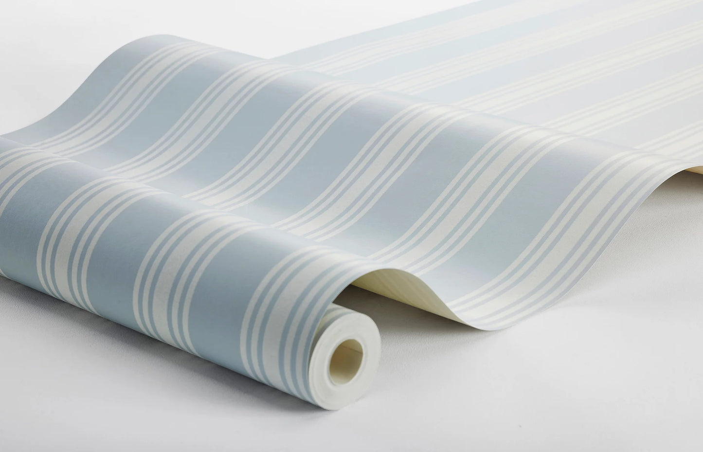 With its cream-colored stripes against a pastel blue background, this Gunnebo wallpaper is inspired by the neoclassical elegance of Gunnebo stately home in Sweden.