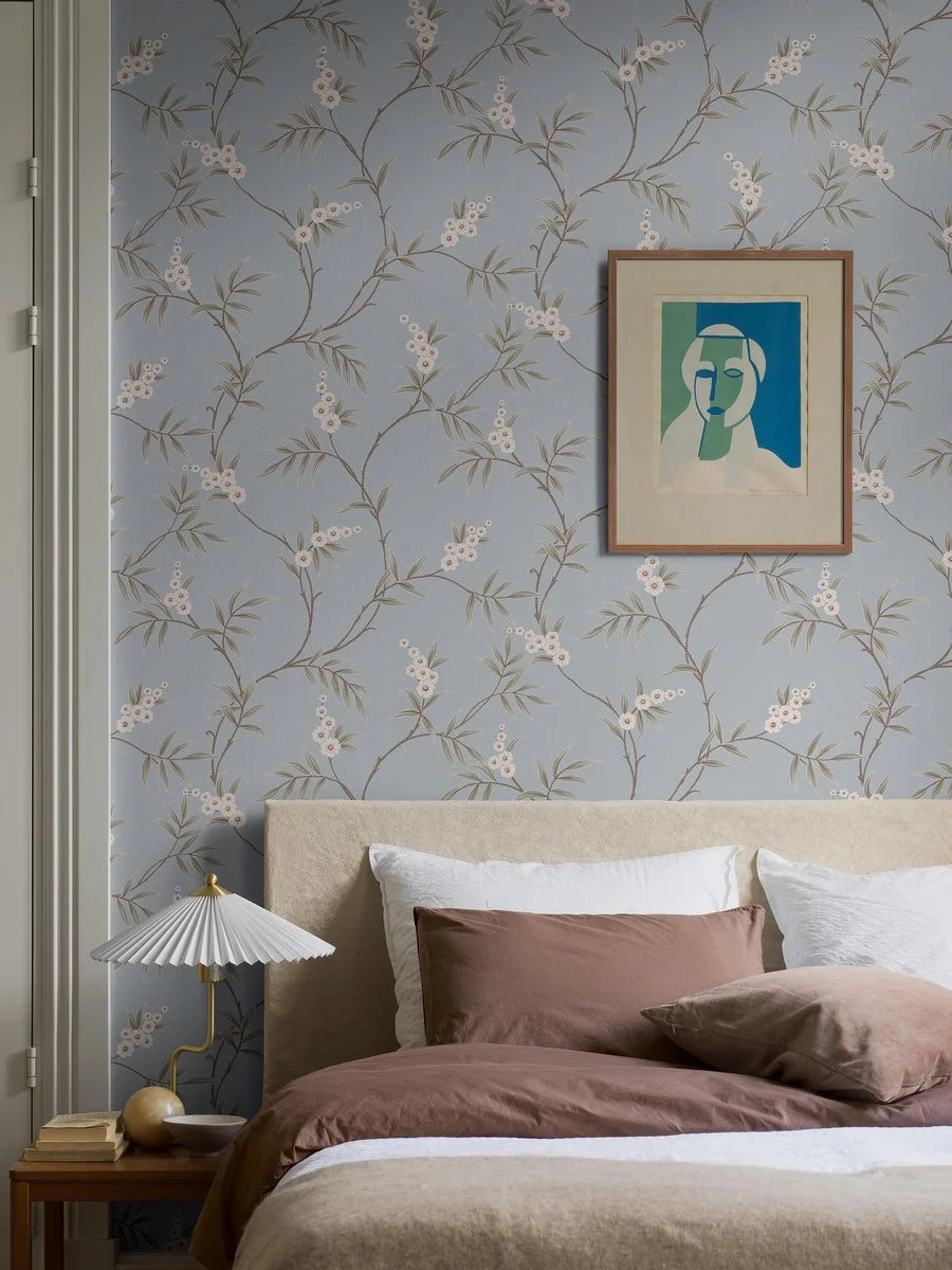 Our Floral Tree wallpaper pairs green leaves with soft white flowers on a serene sky-blue background, blending classic Chinoiserie motif inspiration with a modern aesthetic.