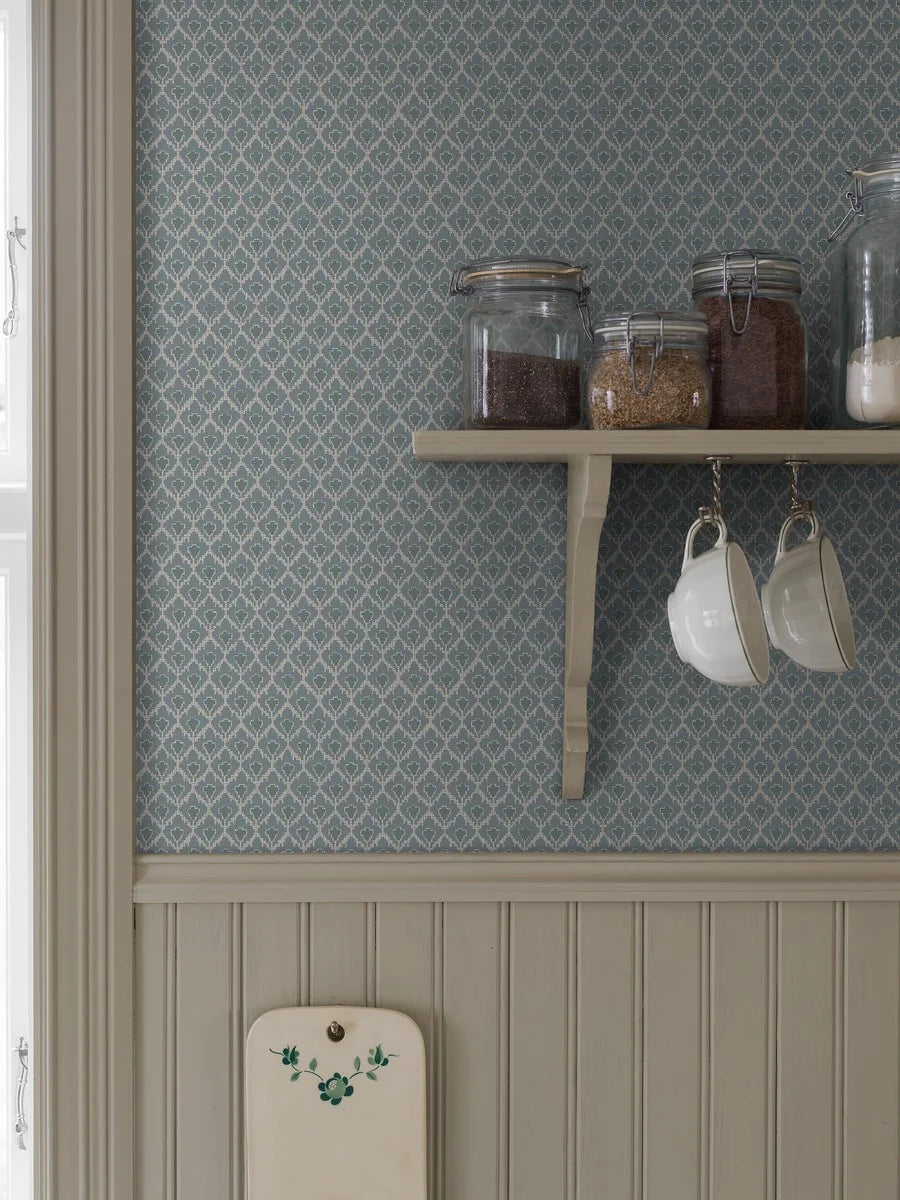 Muted blue tones pair with dark green accents in our Svea wallpaper for a nostalgic palette that is full of depth.