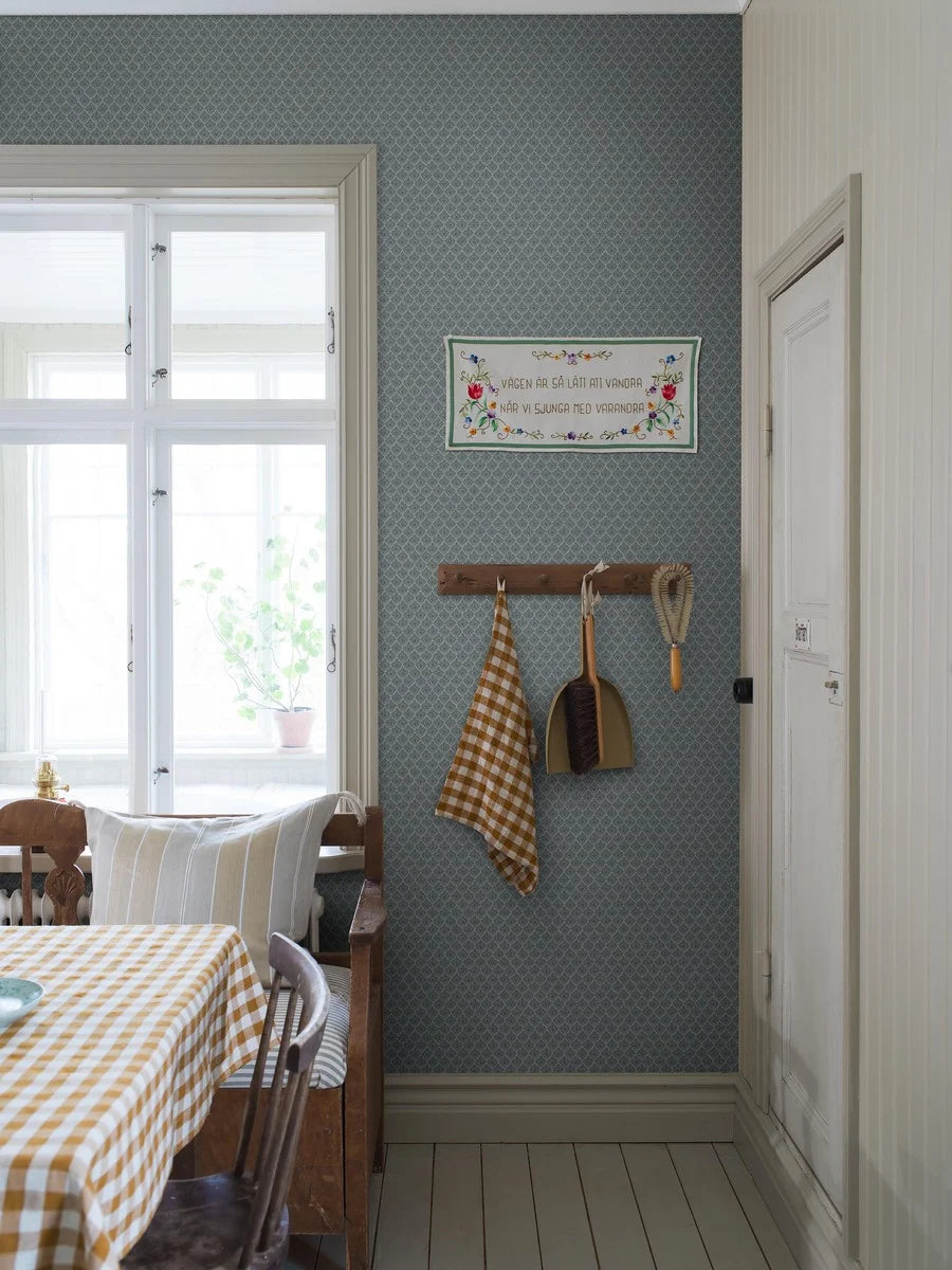 Muted blue tones pair with dark green accents in our Svea wallpaper for a nostalgic palette that is full of depth.