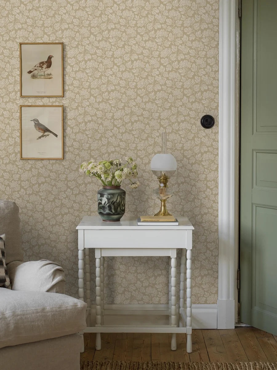 Inspired by the timeless beauty of hawthorns in bloom, our Hagtorn wallpaper in golden beige tones envelops the room in soft foliage and early spring calm.