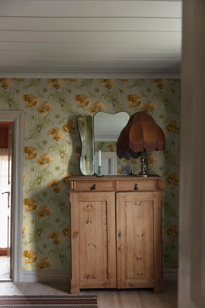 The stately poppies in this Vallmo wallpaper are colored in golden ochre and sandy yellow blooms on a soft green background