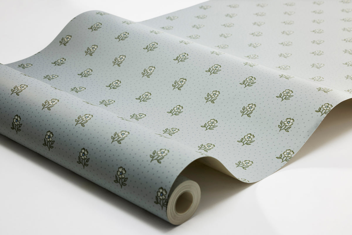 The light blue, small-floral Désirée wallpaper features a hand-painted pattern of charming little flowers on a subtle dotted background.
