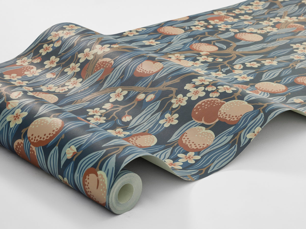 The dark blue Peachtree wallpaper is adorned with apricot-pink peaches and white-pink blossoms in foliage in shades of Blue.
