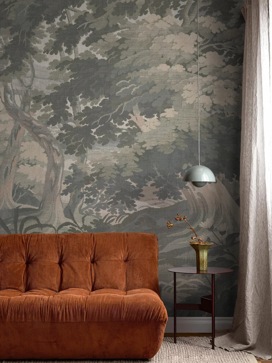 The mural wallpaper Tapestry Landscape resembles a grand tapestry, depicting a rolling landscape with swaying grass and delicate wildflowers beneath lush tree canopies.