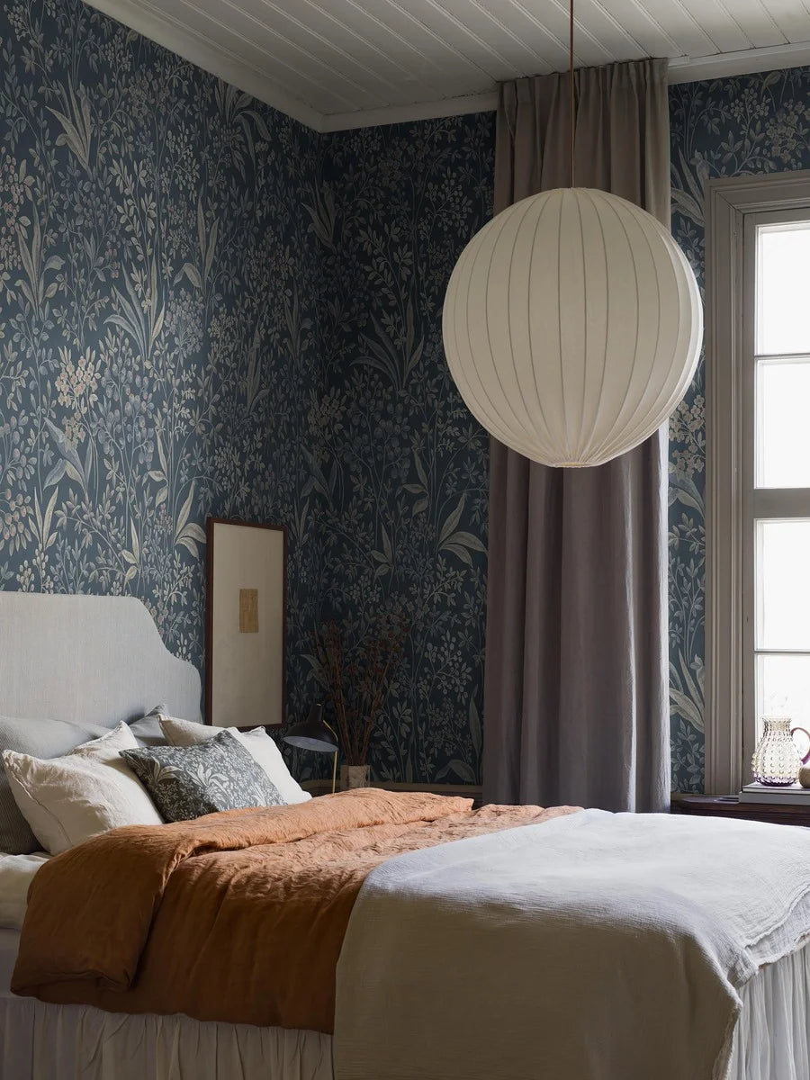 Nocturne Grand is a mural wallpaper featuring winding leaves, small flowers, and seed pods – a large-scale pattern softened by the chalk-like surface of the background.