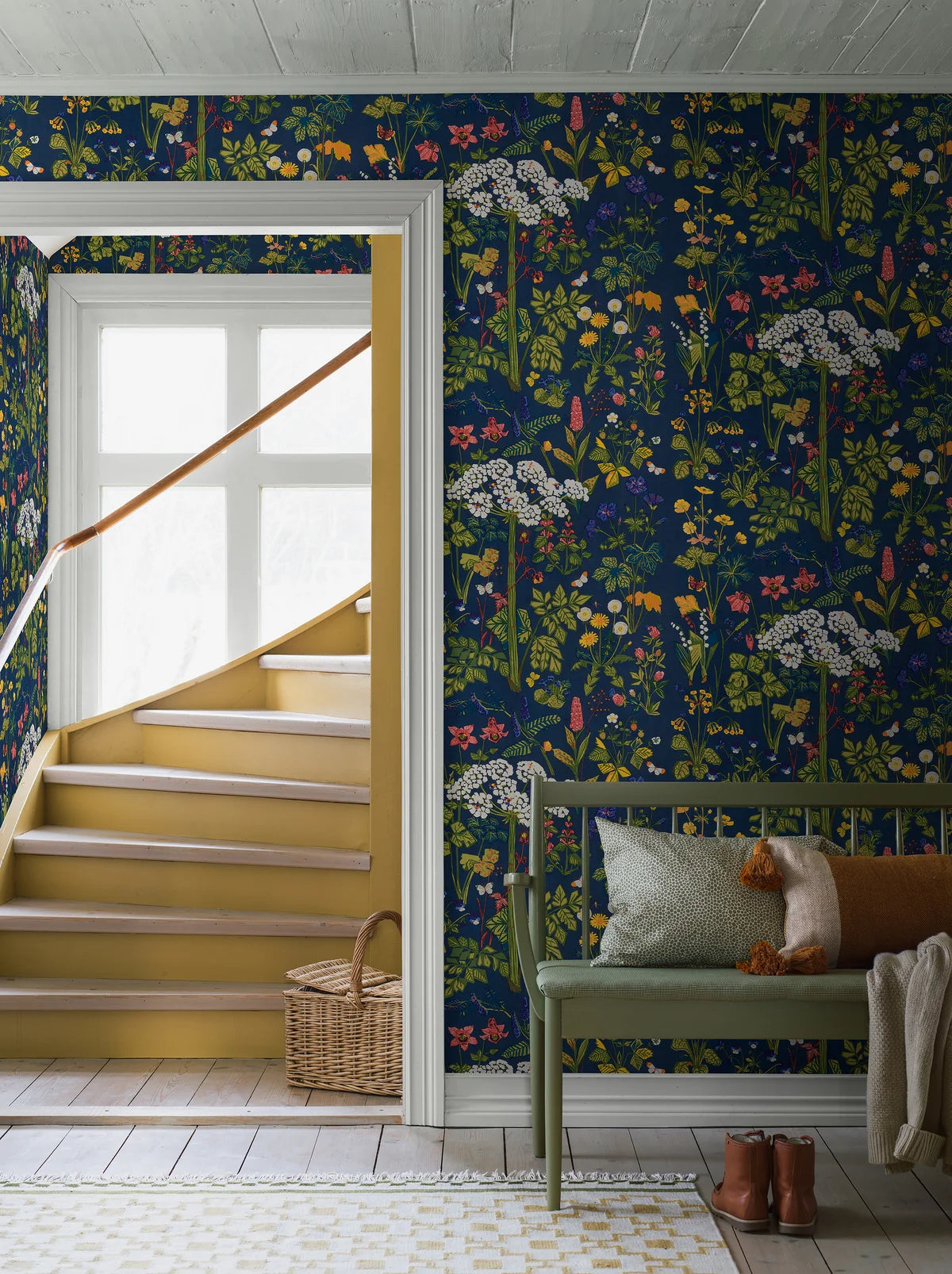 The mural wallpaper Aurora features one of Lisbet Jobs’ most beloved patterns, with flowers such as hogweed, dandelion, cowslip and lily of the valley, here in bright colors on a deep blue ground.
