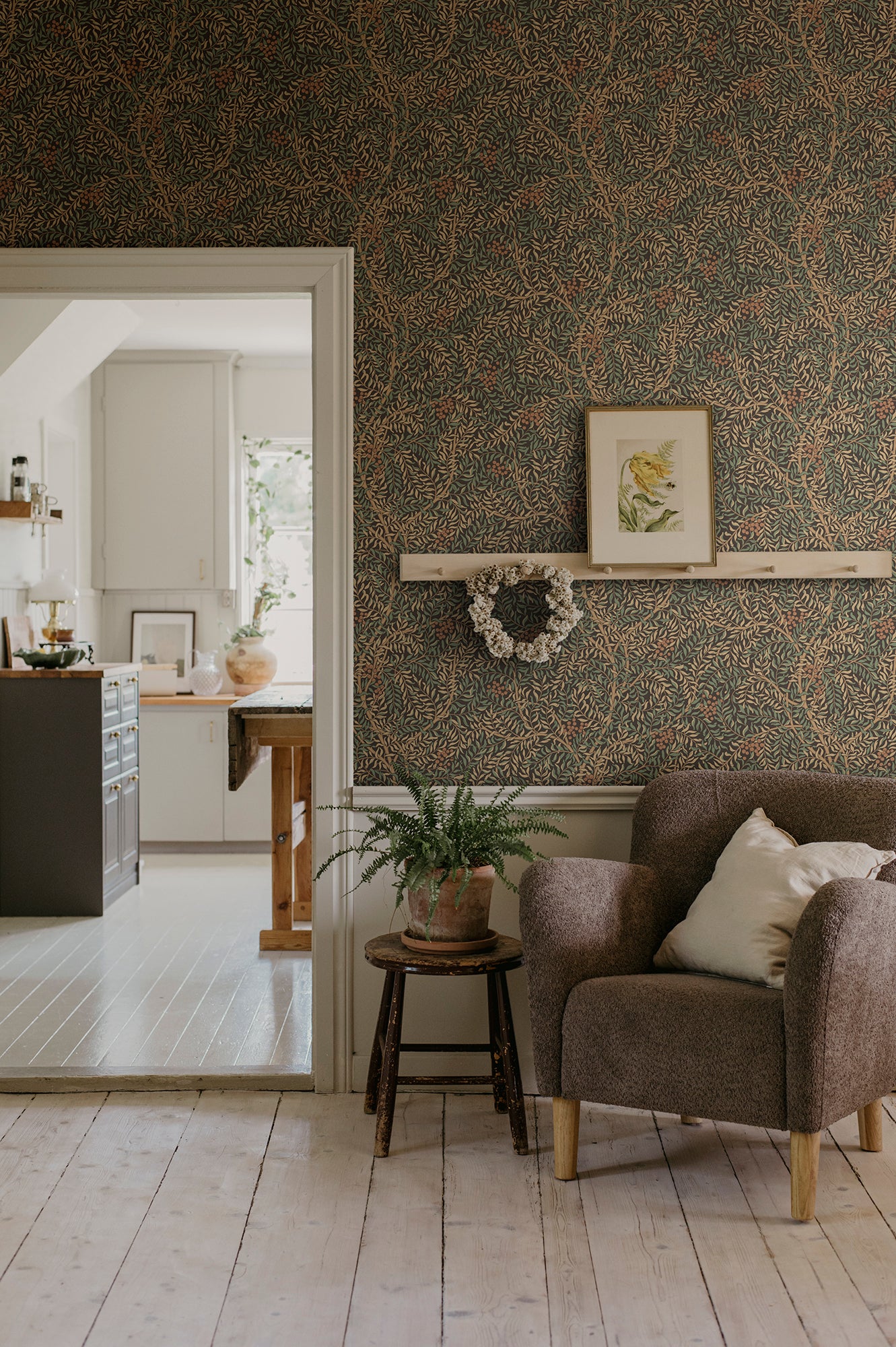 A harmonious surface-printed wallpaper pattern featuring intricate rowan berry branches creates a cozy and welcoming atmosphere with its stylized and enveloping design.