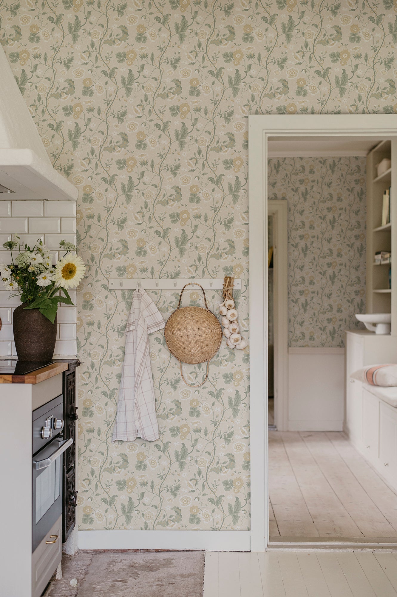 Japanese anemones, cup-and-saucer vines, and avens intertwined offer a softly verdant Arts & Crafts-inspired wallpaper with intricate details and an enveloping character.