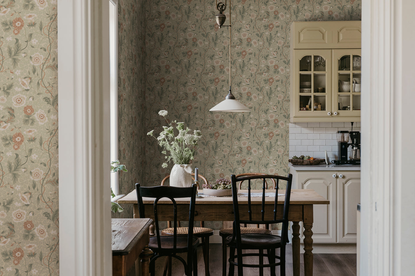 Japanese anemones, cup-and-saucer vines, and avens intertwined offer a softly verdant Arts & Crafts-inspired wallpaper with intricate details and an enveloping character.