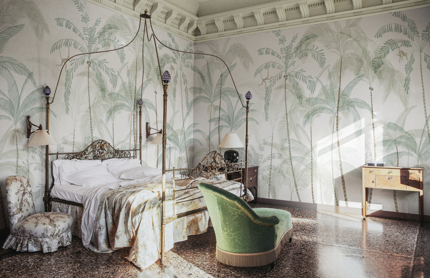Hand-painted swaying palm trees with a vintage feel create a lush, airy scenography with monkeys swinging between the treetops. Wallpaper Louie, Light Green features a serene white background accented with delicate light green and soft beige hues.