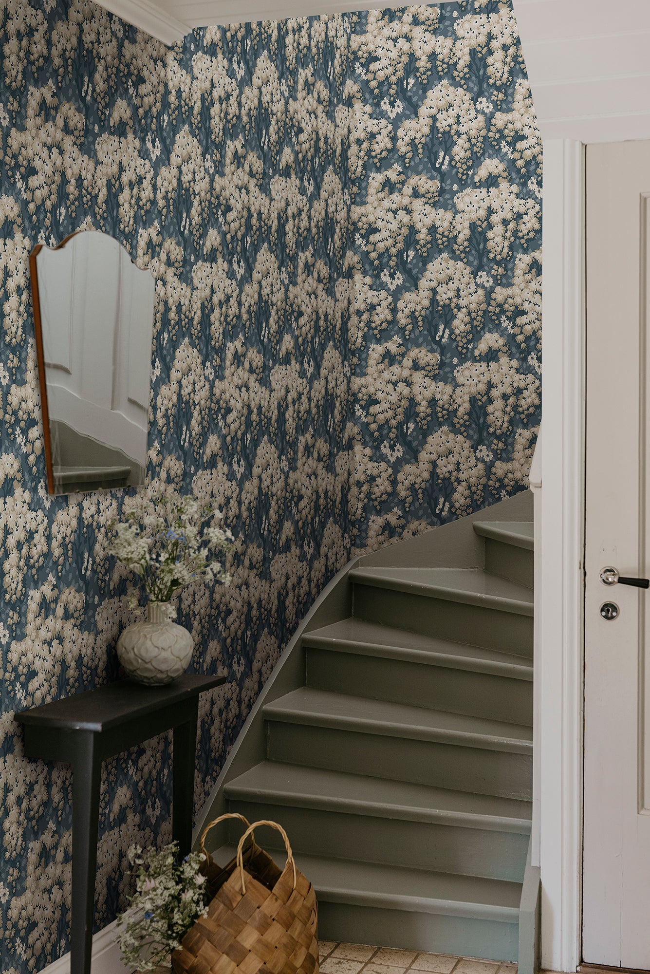 Lush tree canopies against a meadow of daisies create a harmonious, large-patterned wallpaper curtain on the wall.