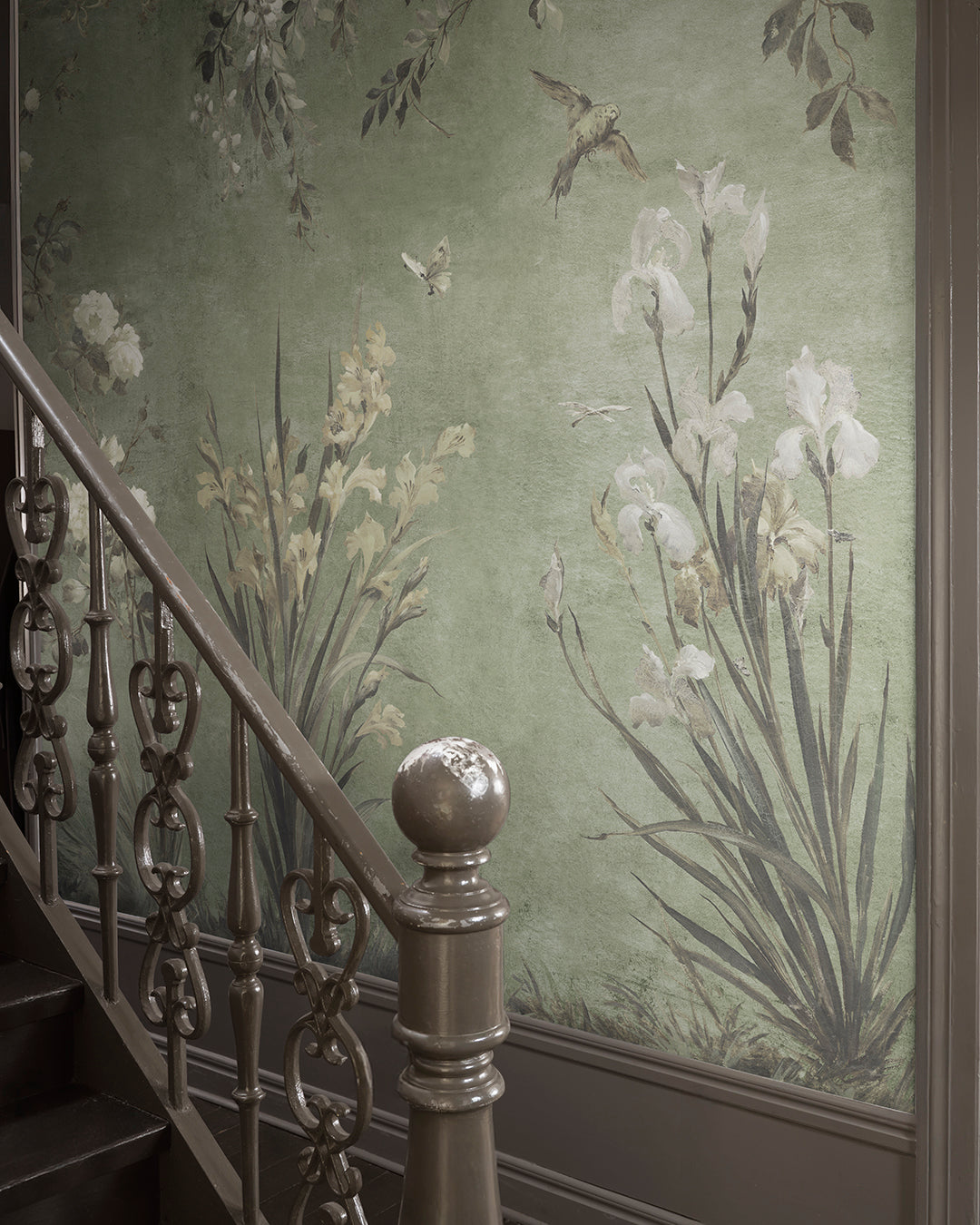 Adorn your walls with the Nicola mural, where antique charm meets nature's embrace. Graceful flowers and whimsical birds gently unfurl against a serene sage green backdrop, creating a romantic, hand-painted elegance.