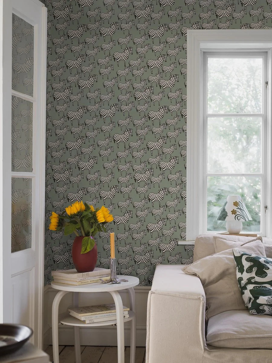 A herd of black and white zebras move gracefully across a gentle green backdrop in our Zebra wallpaper. Inspired by Lisa Larson’s much-loved ceramic zebra, originally created in 1957, this version of our wallpaper has a milder palette that preserves the design’s lively rhythm and charm.