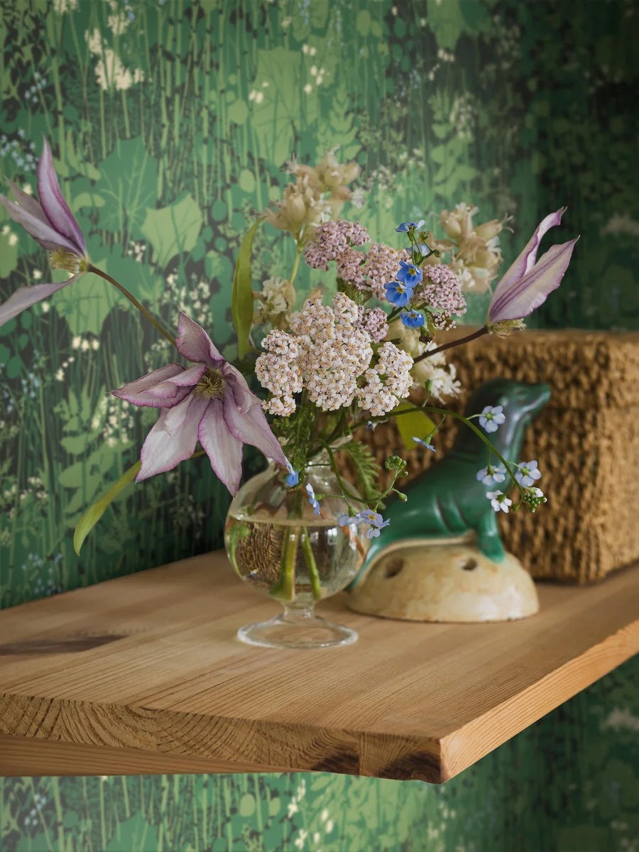 Capturing a lush green verge, our Dikesren wallpaper is a vibrant tribute to nature’s beauty. Originally created for textile in 1944, this iconic design by Arne Jacobsen features ferns, forget-me-nots, and wildflowers on deep green ground.