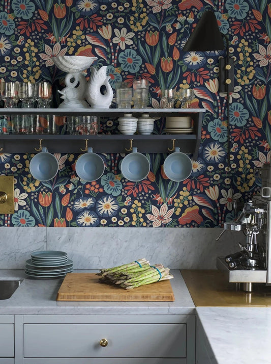 Colored in cheerful tones of green, turquoise, yellow, red and white on a deep dark blue background, our Trädgården wallpaper in a surface print brings a garden scene to life on your walls.