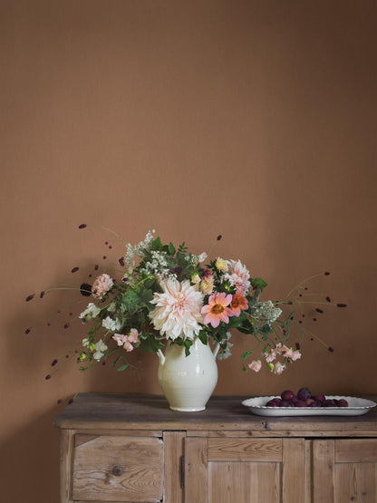 Deep Terra is a rich terracotta-colored wallpaper with a warm, earthy character. The wallpaper has a tactile linen texture that gives the color depth and a vibrant expression
