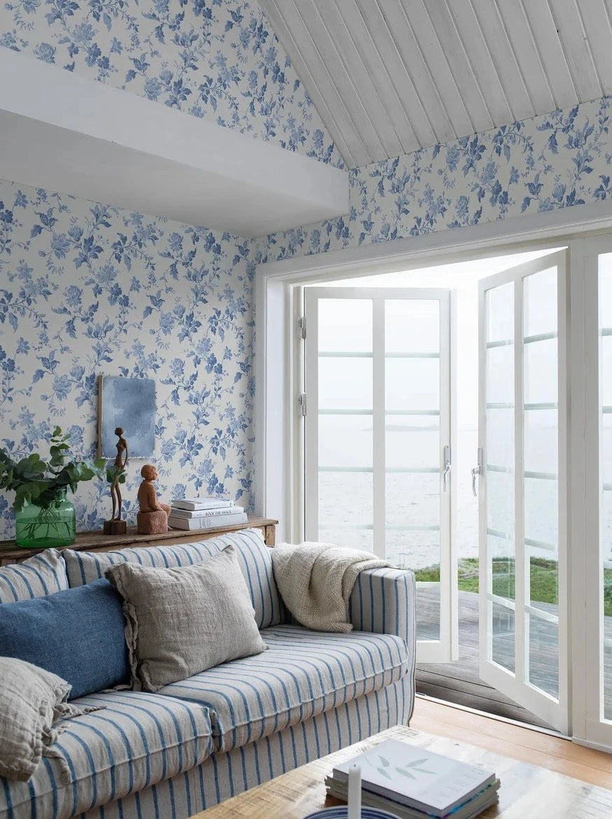 Reviving the charm of the late 1800s, our Blomslinga wallpaper in a traditional surface print, features delightful blue flowers and leaves on a fresh white base.