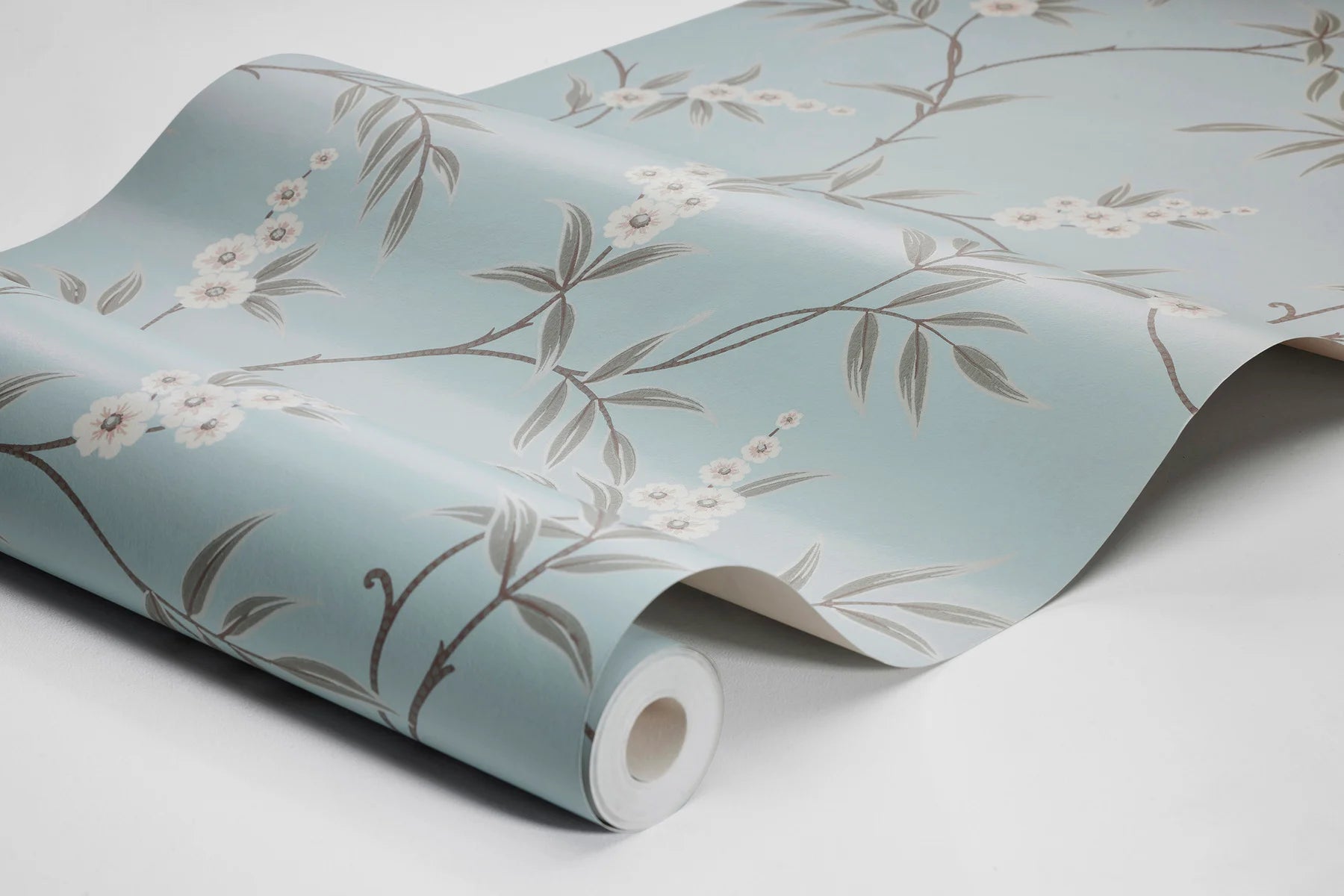Our Floral Tree wallpaper pairs green leaves with soft white flowers on a serene sky-blue background, blending classic Chinoiserie motif inspiration with a modern aesthetic. 