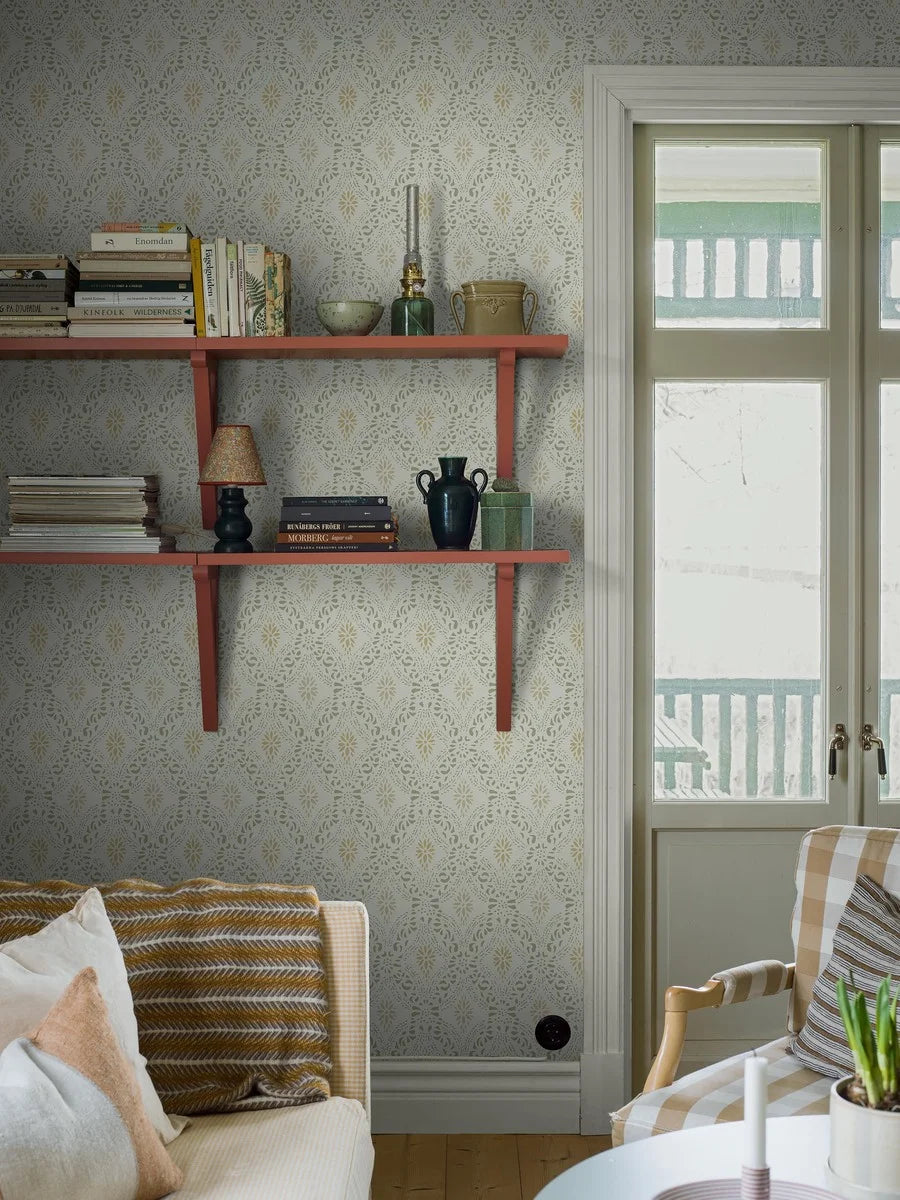 Colored in a bright yet cosy color scheme, our Kvarnholmen wallpaper features a stencil design, printed in soft green and ochre over a warm white background, with accents of sand-toned beige.