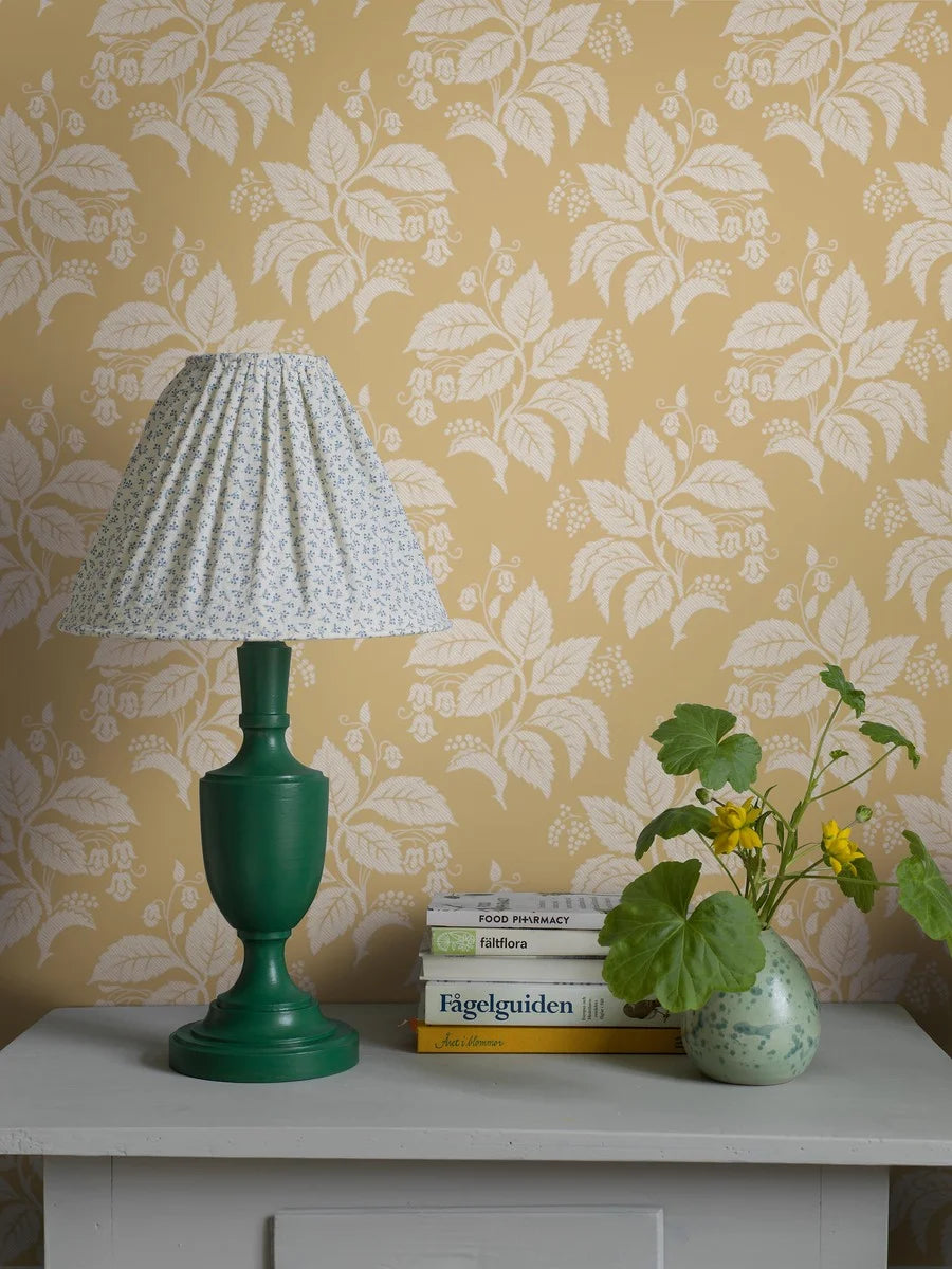 Our Tengbergska wallpaper offers a warm and cheerful take on an early 19th-century French wallpaper design, featuring a grey and white print on a yellow background.