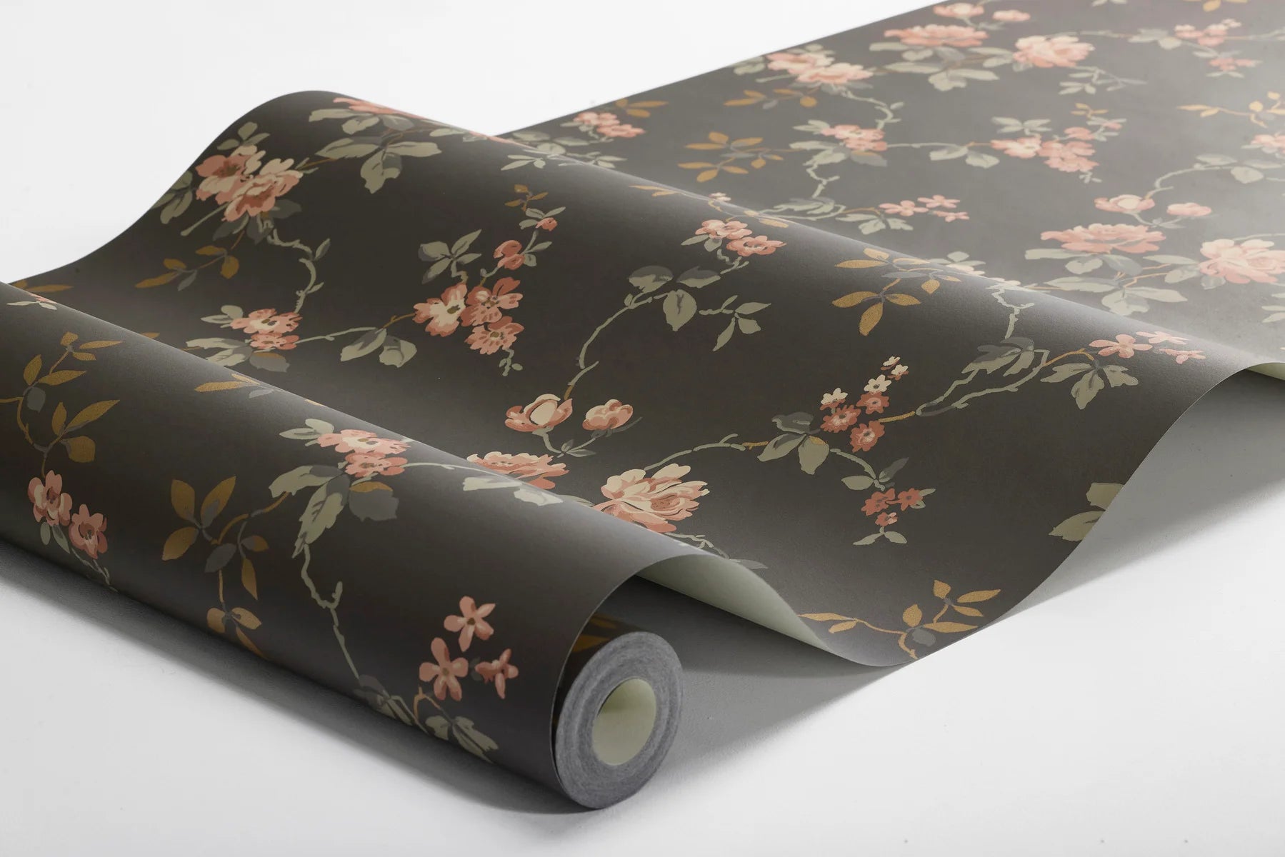  Delicate red and pink roses and grey-brown and copper-toned leaves unfurl across a deep, dramatic brown base in this Värmdö wallpaper. 