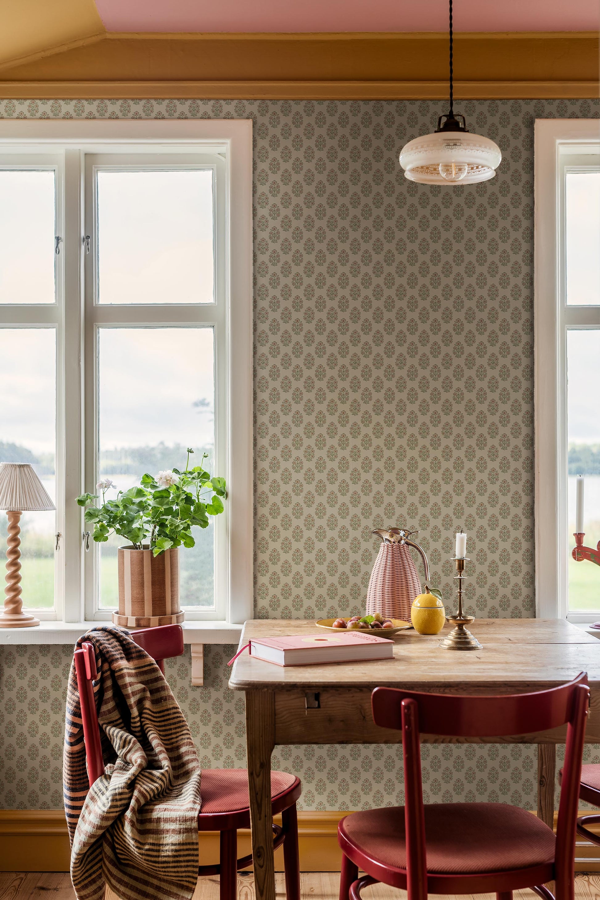 Set against a cream-white background, this Sibylla wallpaper is adorned with pale pink flowers with apricot centres and leaves in soft green tones, arranged in gentle, rhythmic bouquets.