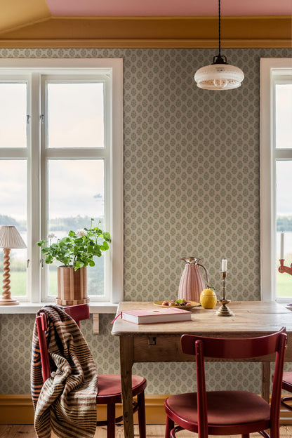 Set against a cream-white background, this Sibylla wallpaper is adorned with pale pink flowers with apricot centres and leaves in soft green tones, arranged in gentle, rhythmic bouquets.