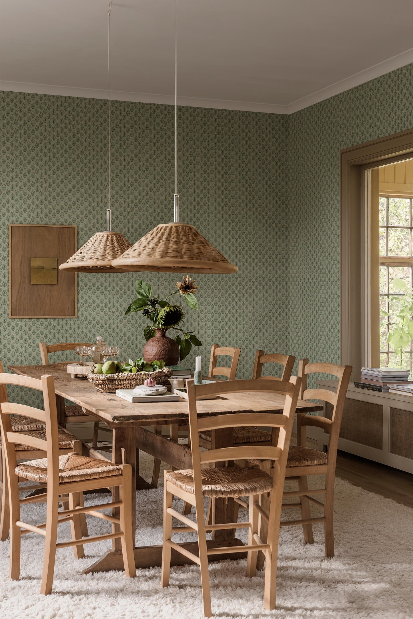 Set against a soft green background, this Sibylla wallpaper is decorated with stylised bouquets in light pink, yellow, and blue green. 