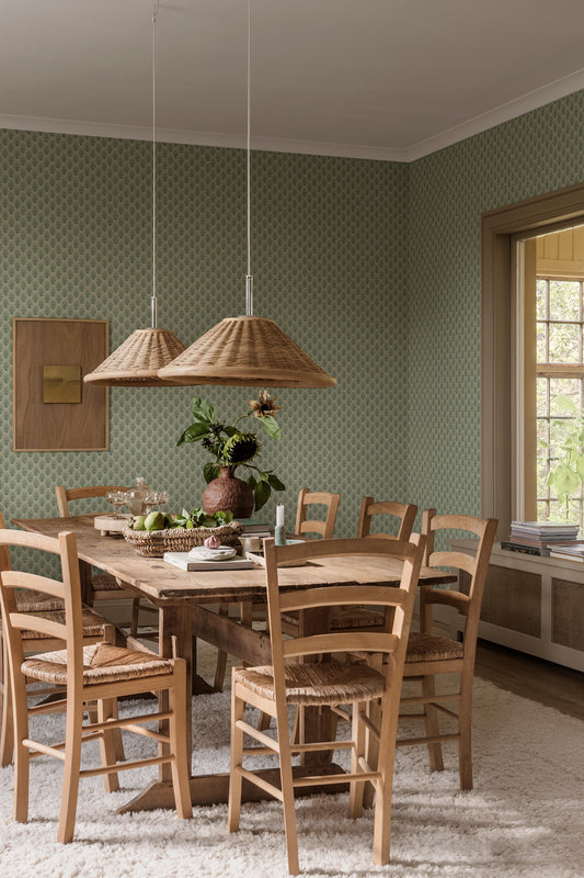 Set against a soft green background, this Sibylla wallpaper is decorated with stylised bouquets in light pink, yellow, and blue green. 