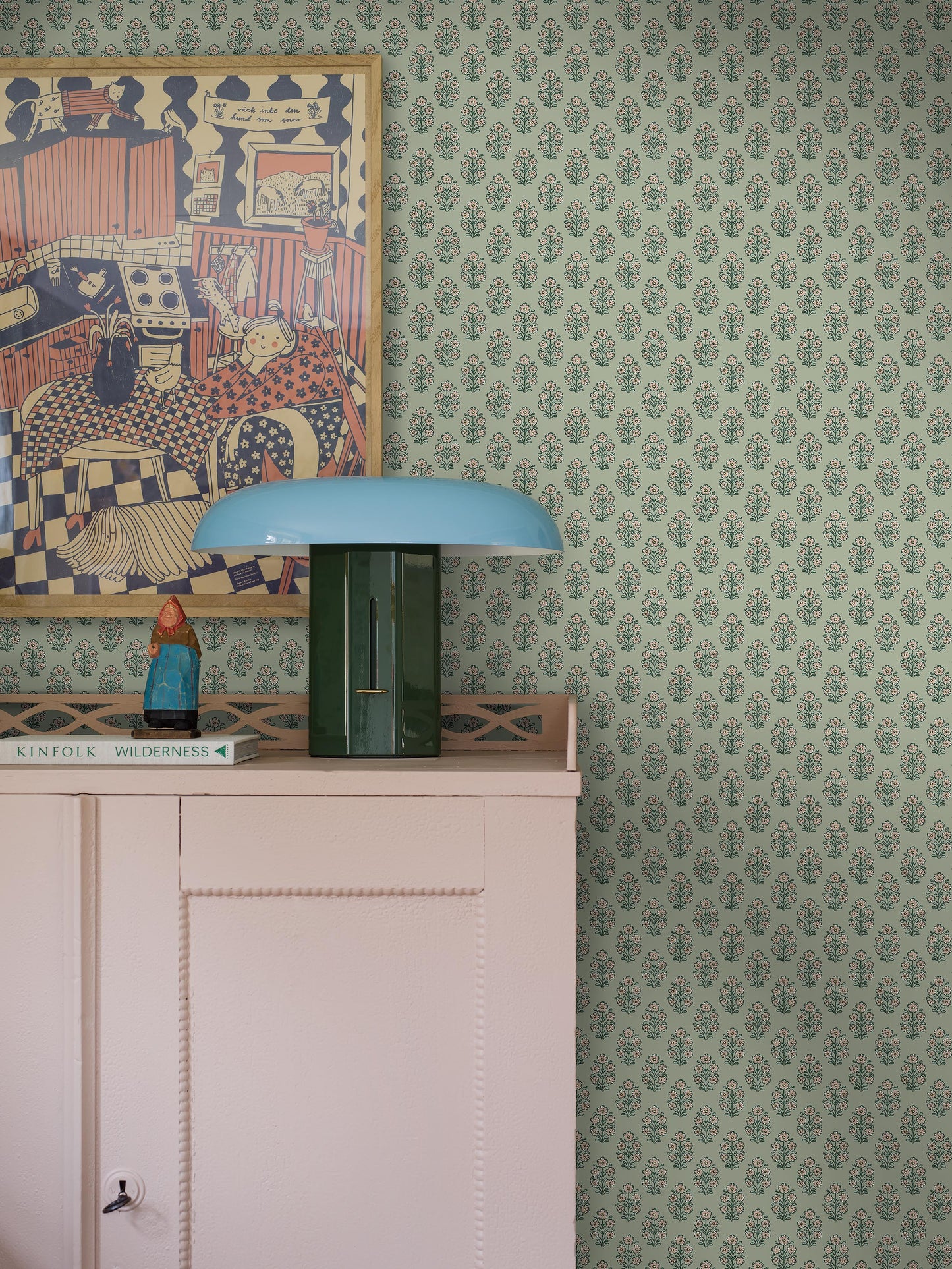 Set against a soft green background, this Sibylla wallpaper is decorated with stylised bouquets in light pink, yellow, and blue green. 