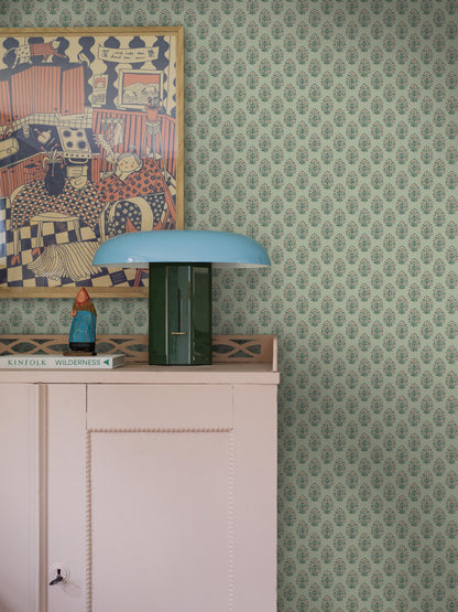 Set against a soft green background, this Sibylla wallpaper is decorated with stylised bouquets in light pink, yellow, and blue green. 