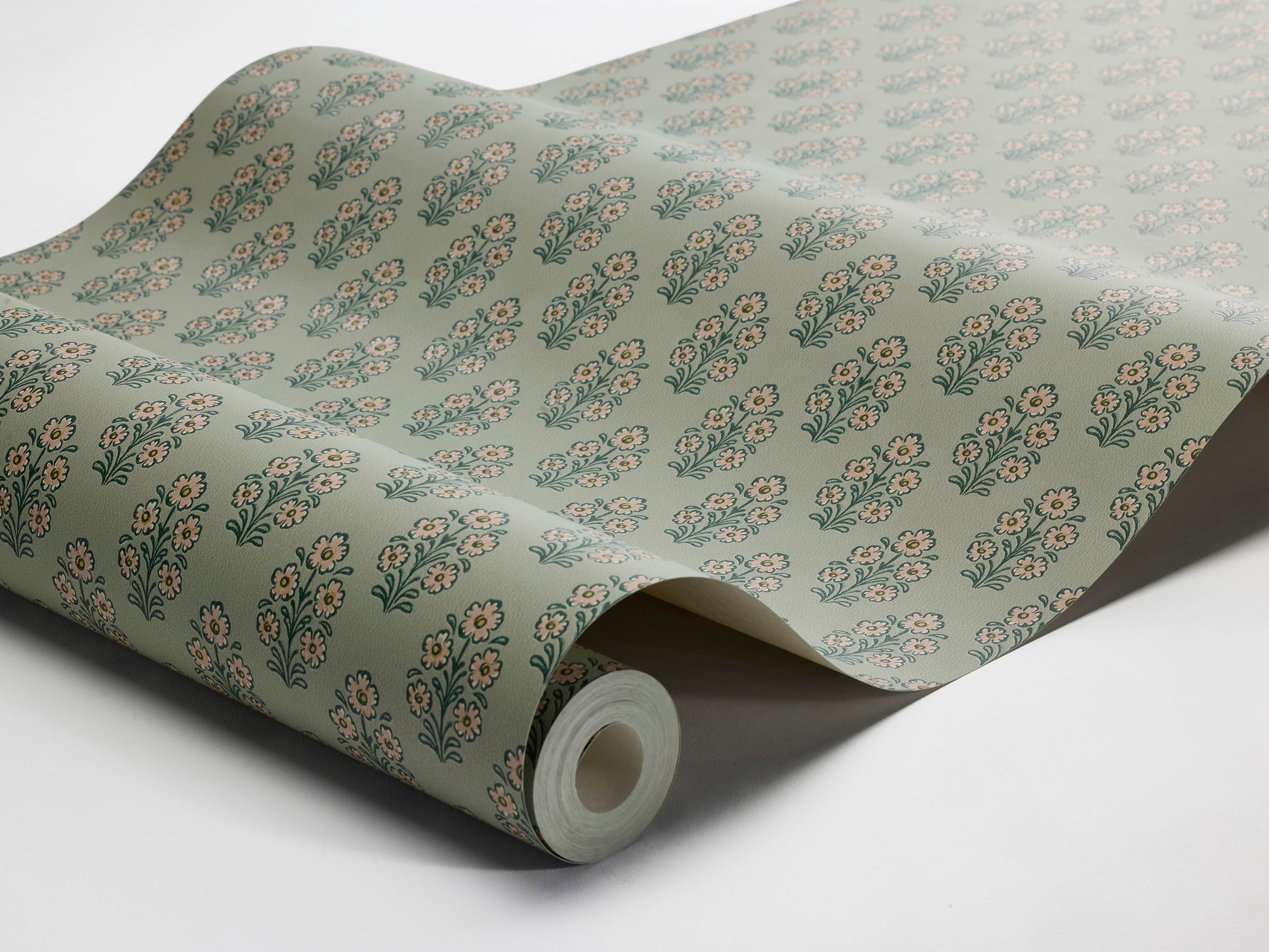 Set against a soft green background, this Sibylla wallpaper is decorated with stylised bouquets in light pink, yellow, and blue green. 