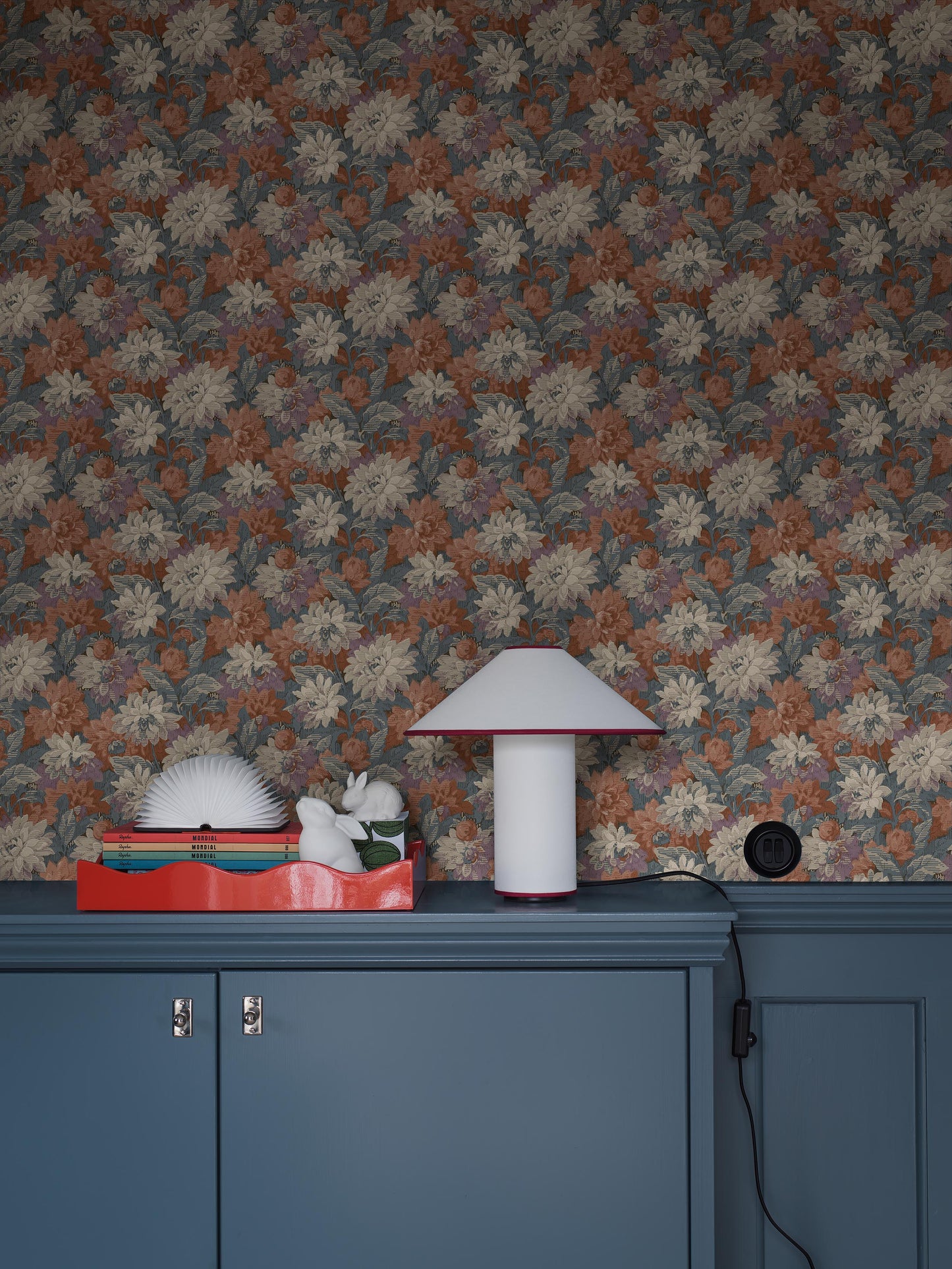 Colored in deep blue, brick red, and soft grey-purple tones, our Delilah wallpaper captures a dramatic and refined aesthetic. 
