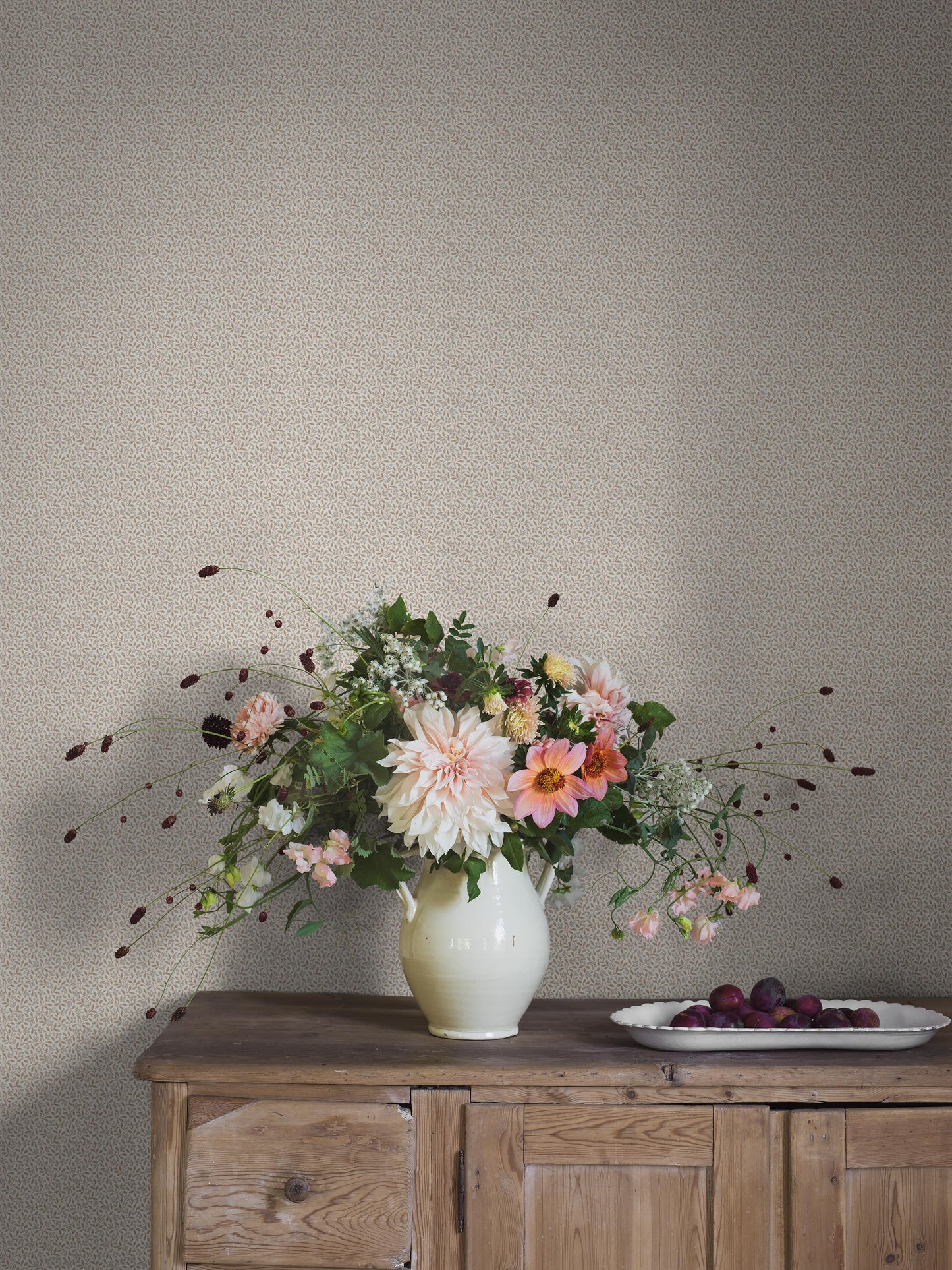 In warm beige tones, our Ida wallpaper reveals a graceful vine pattern of soft leaves and slender stems.