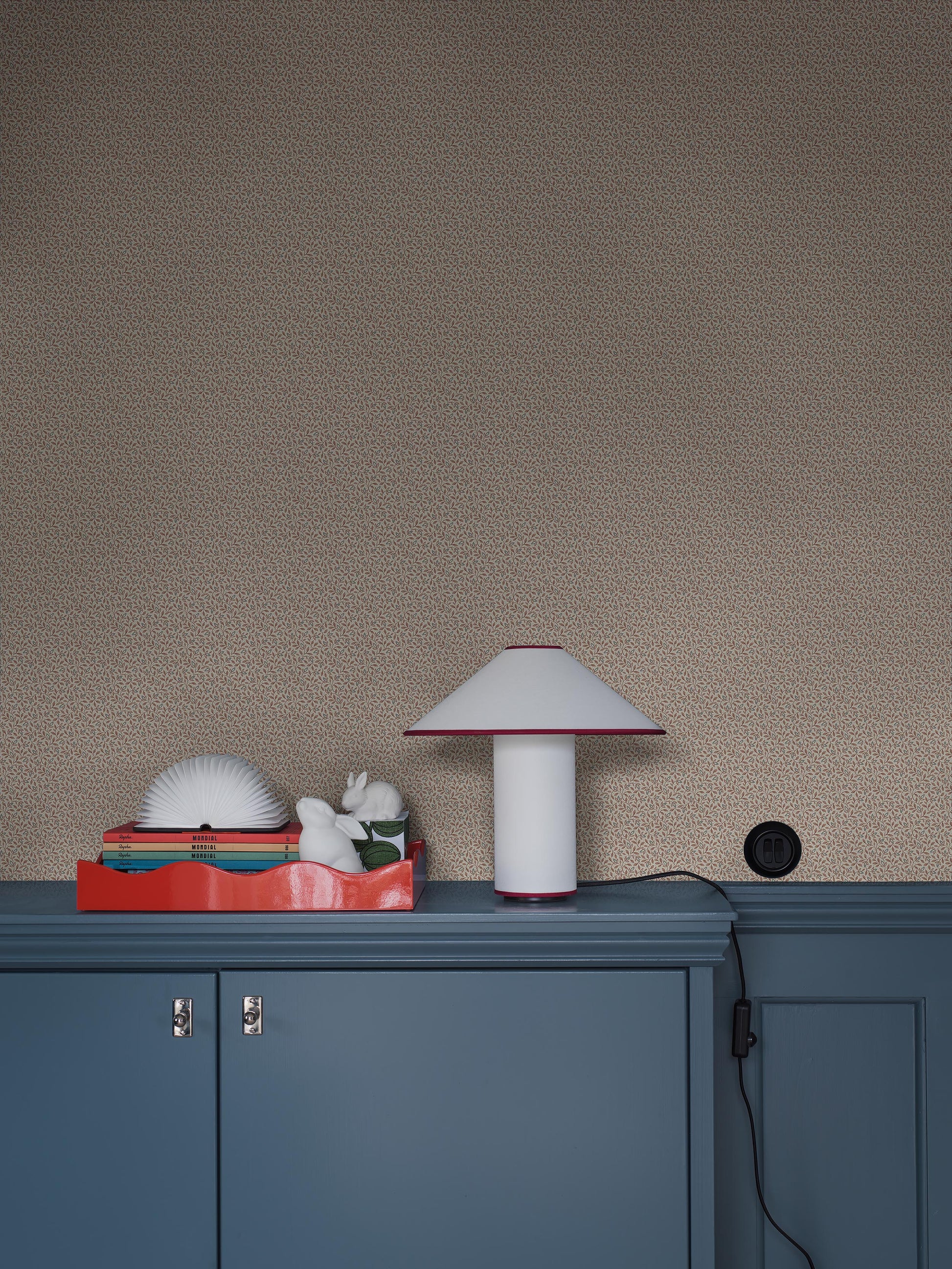 Colored in a light grey-beige tone, our Ida wallpaper reveals a delicate vine motif highlighted with pale red, grey-blue, and brown detailing. 