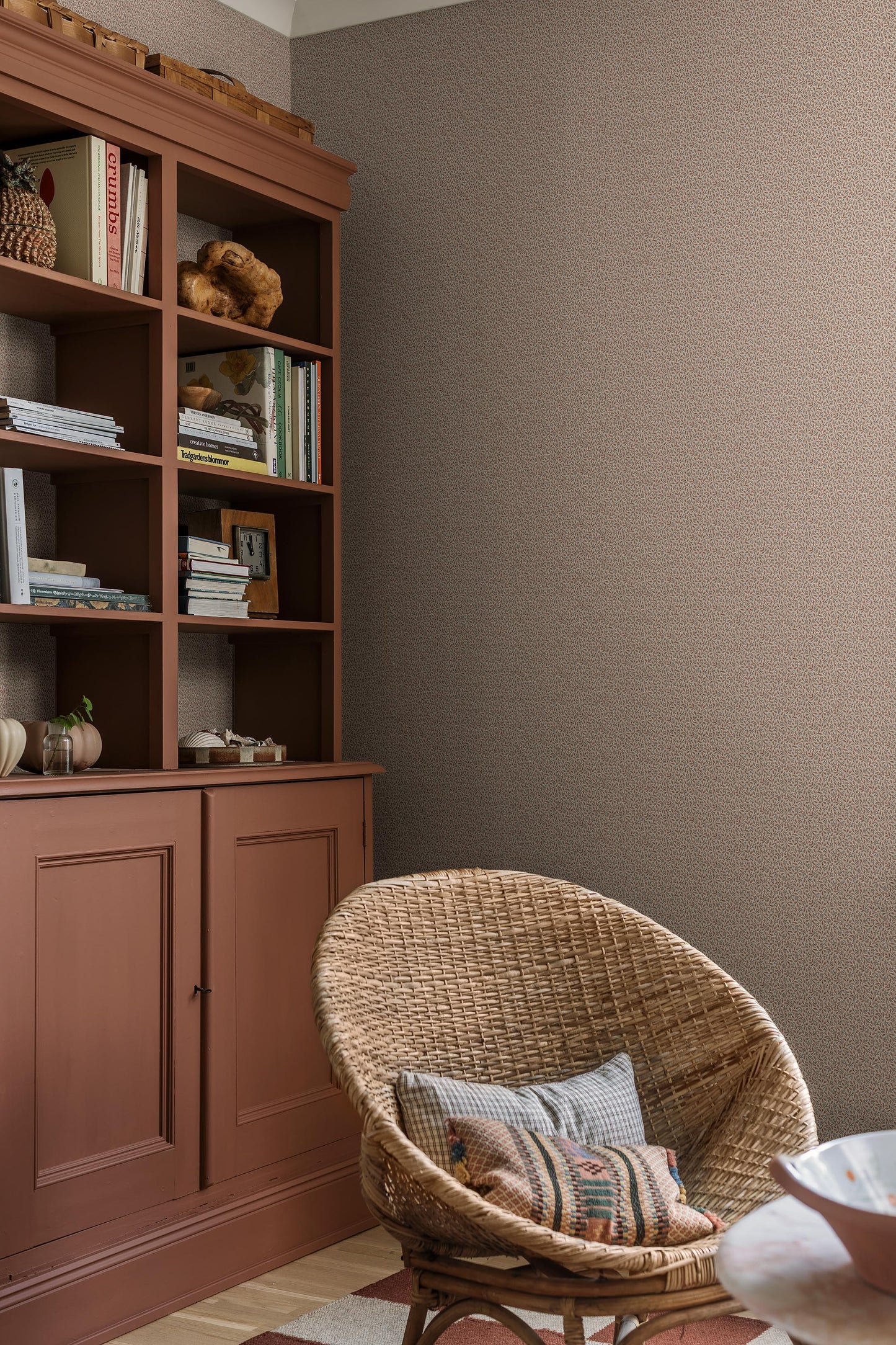 Colored in a light grey-beige tone, our Ida wallpaper reveals a delicate vine motif highlighted with pale red, grey-blue, and brown detailing. 