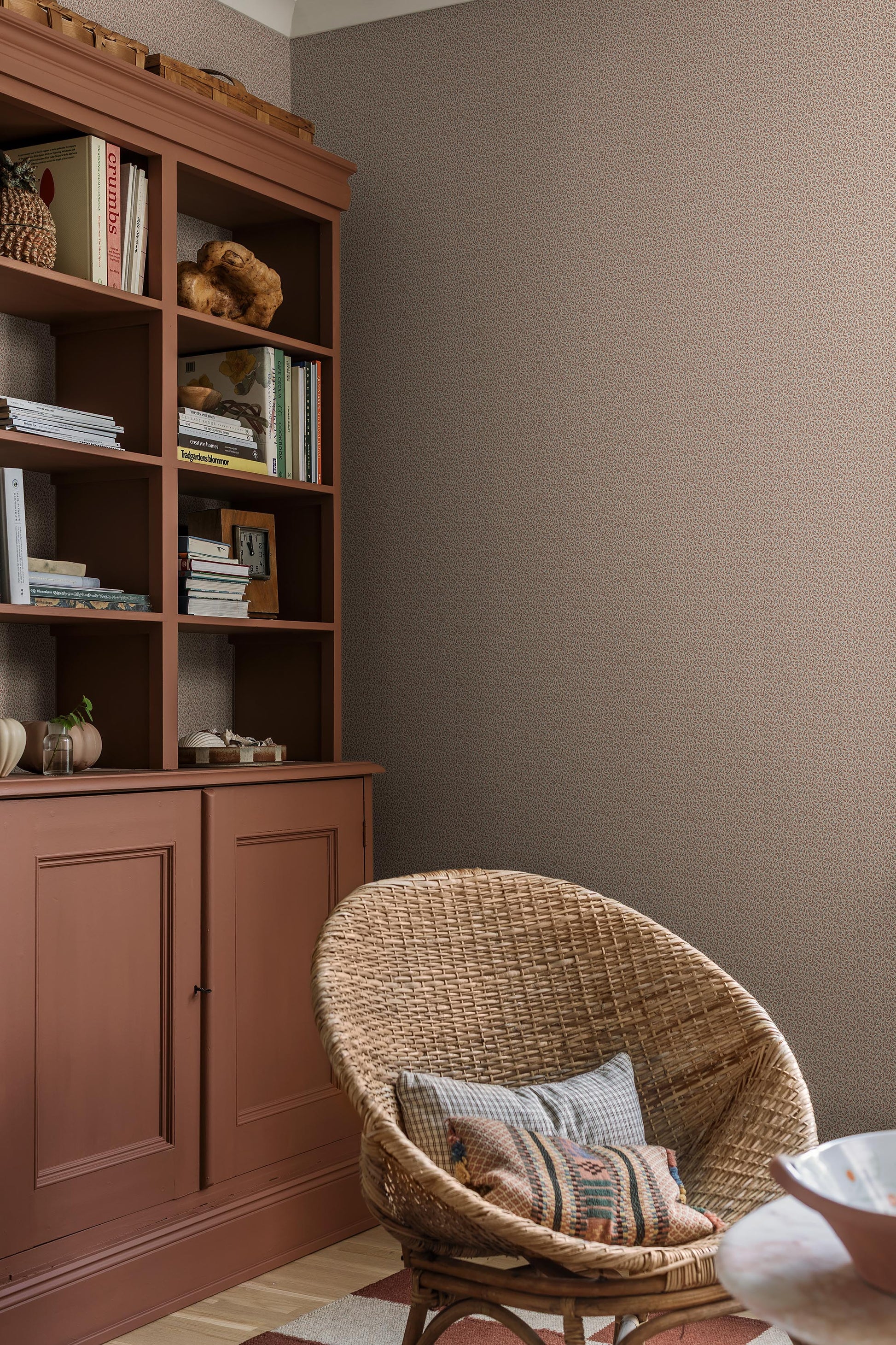 Colored in a light grey-beige tone, our Ida wallpaper reveals a delicate vine motif highlighted with pale red, grey-blue, and brown detailing. 