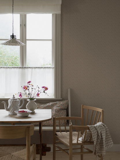 Colored in warm, soft brown tones, our Ida wallpaper features intertwining stems adorned with lush leaves and petite petals that wind naturally across the surface.