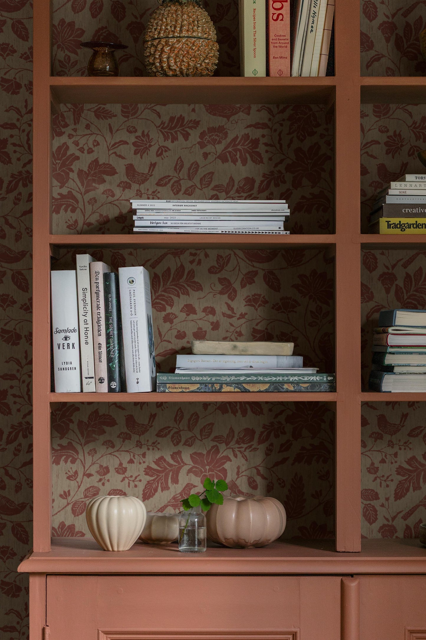 Colored in muted reddish-brown tones on a soft grey-brown base, our Isidor wallpaper reveals a graceful scene of birds and blossoms nestled among leafy branches. 