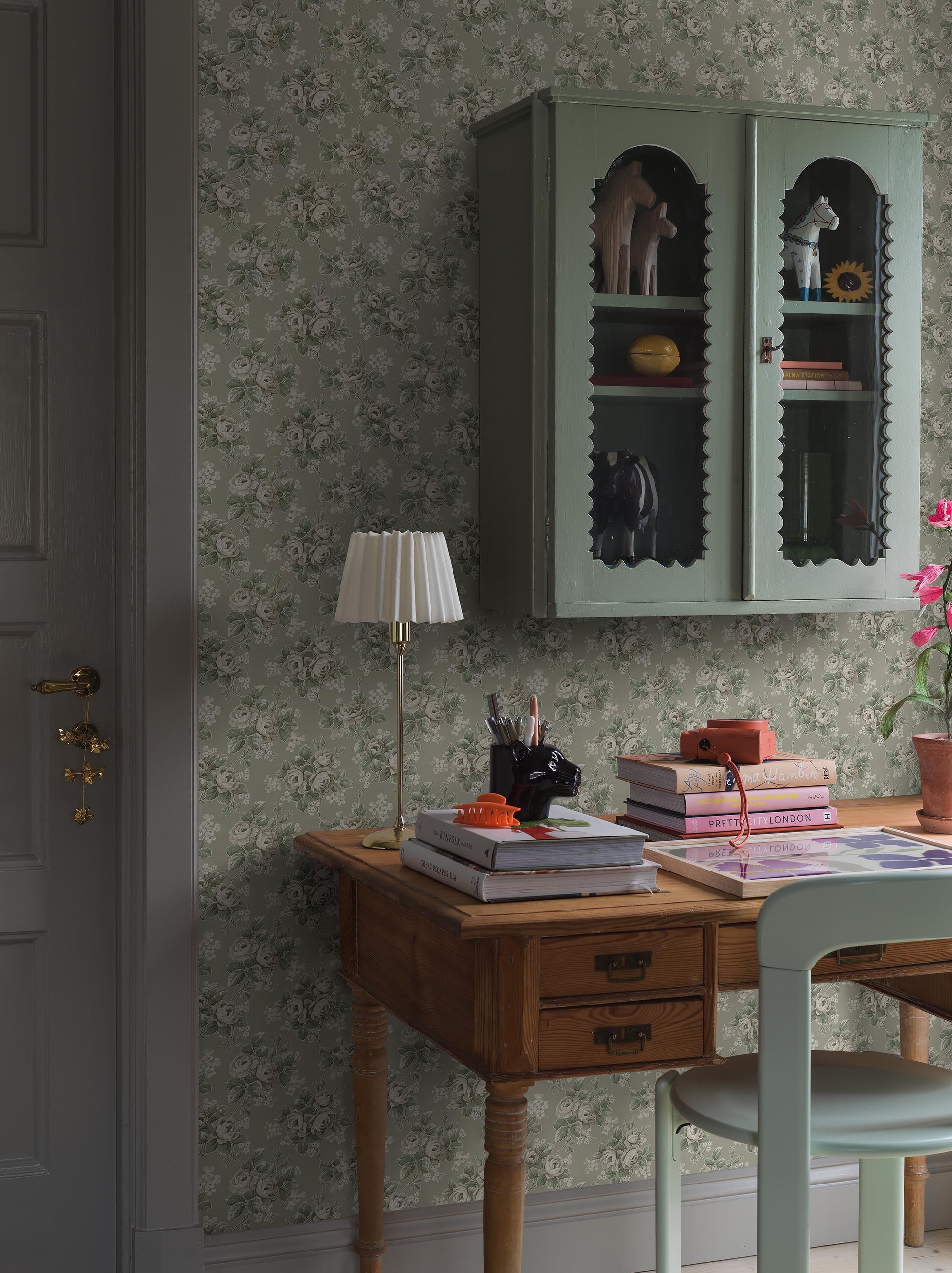 Set on a light linden-green background, our Helena wallpaper displays blooming climbing roses alongside small white flowers in tones of beige, green, and white.