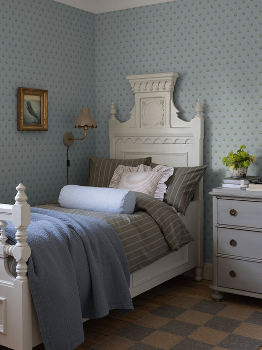  The light blue, small-floral Désirée wallpaper features a hand-painted pattern of charming little flowers on a subtle dotted background. 