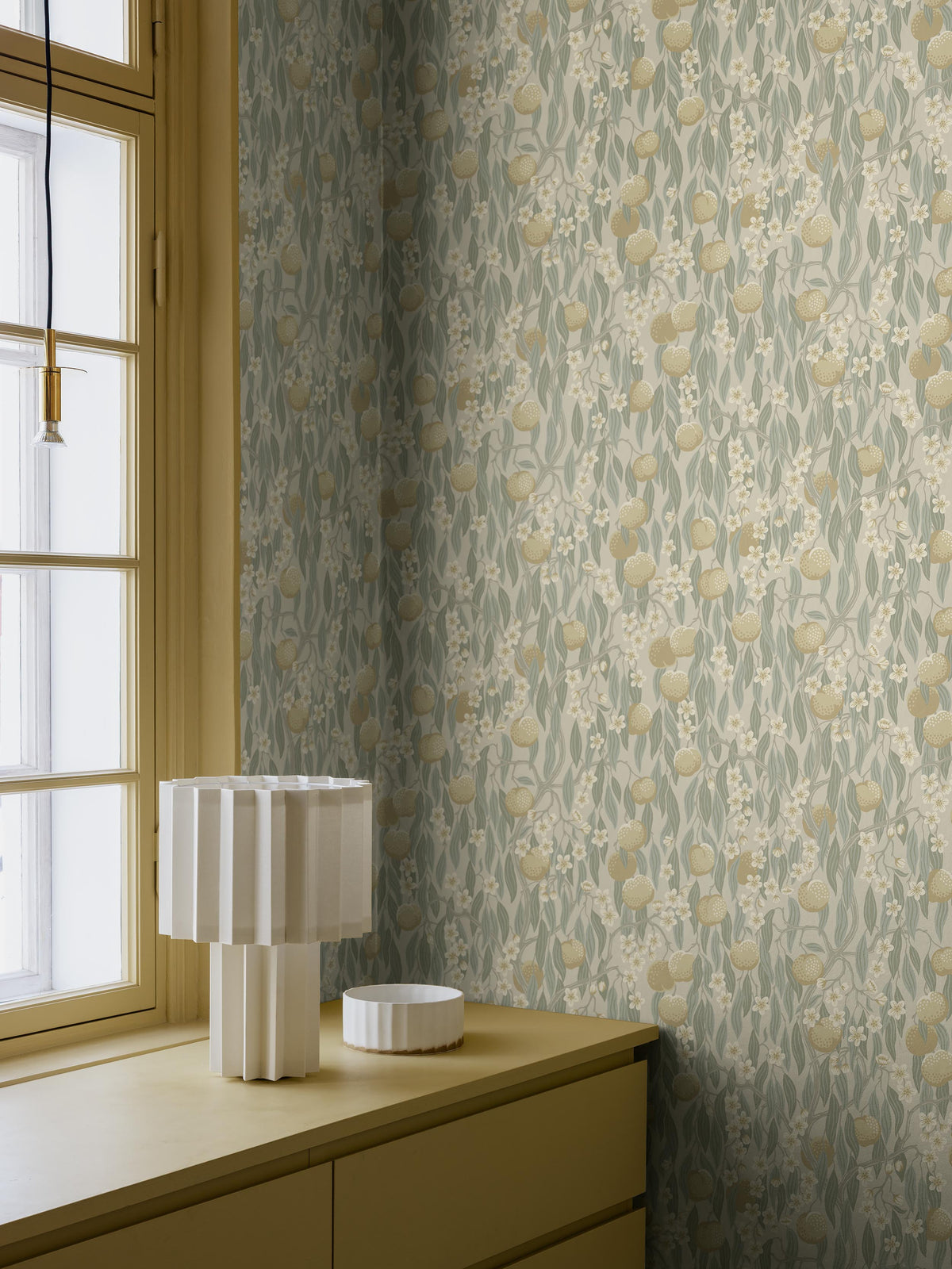 Like an elegant drapery of stylized fruits, flowers and leaves, the Persikoträd wallpaper dresses the room’s walls. The pattern is hand-painted in gouache and then traditionally printed as wallpaper using the glue-printing technique.