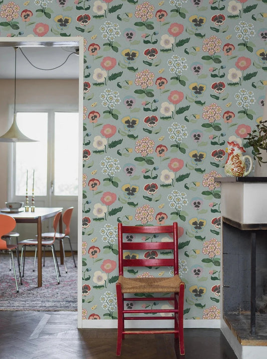 Set against a gentle grey-blue backdrop, Posy wallpaper imparts a cheerful atmosphere to rooms with its detailed and colorful floral design.