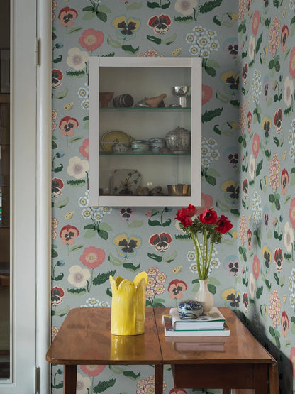 Set against a gentle grey-blue backdrop, Posy wallpaper imparts a cheerful atmosphere to rooms with its detailed and colorful floral design.