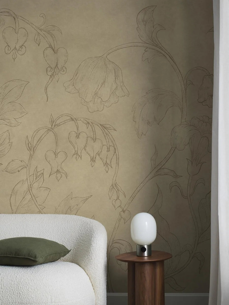 Burning Heart is a warm and soothing mural wallpaper with delicate flowers stretching towards the ceiling. Delicate bleeding hearts and bellflowers drawn in pencil gray on a muted yellow background, discreetly marbled with beautiful patina.