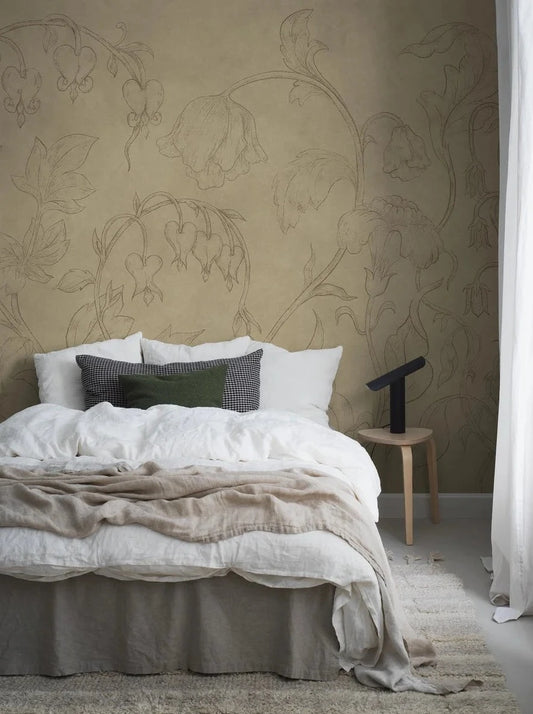 Burning Heart is a warm and soothing mural wallpaper with delicate flowers stretching towards the ceiling. Delicate bleeding hearts and bellflowers drawn in pencil gray on a muted yellow background, discreetly marbled with beautiful patina.
