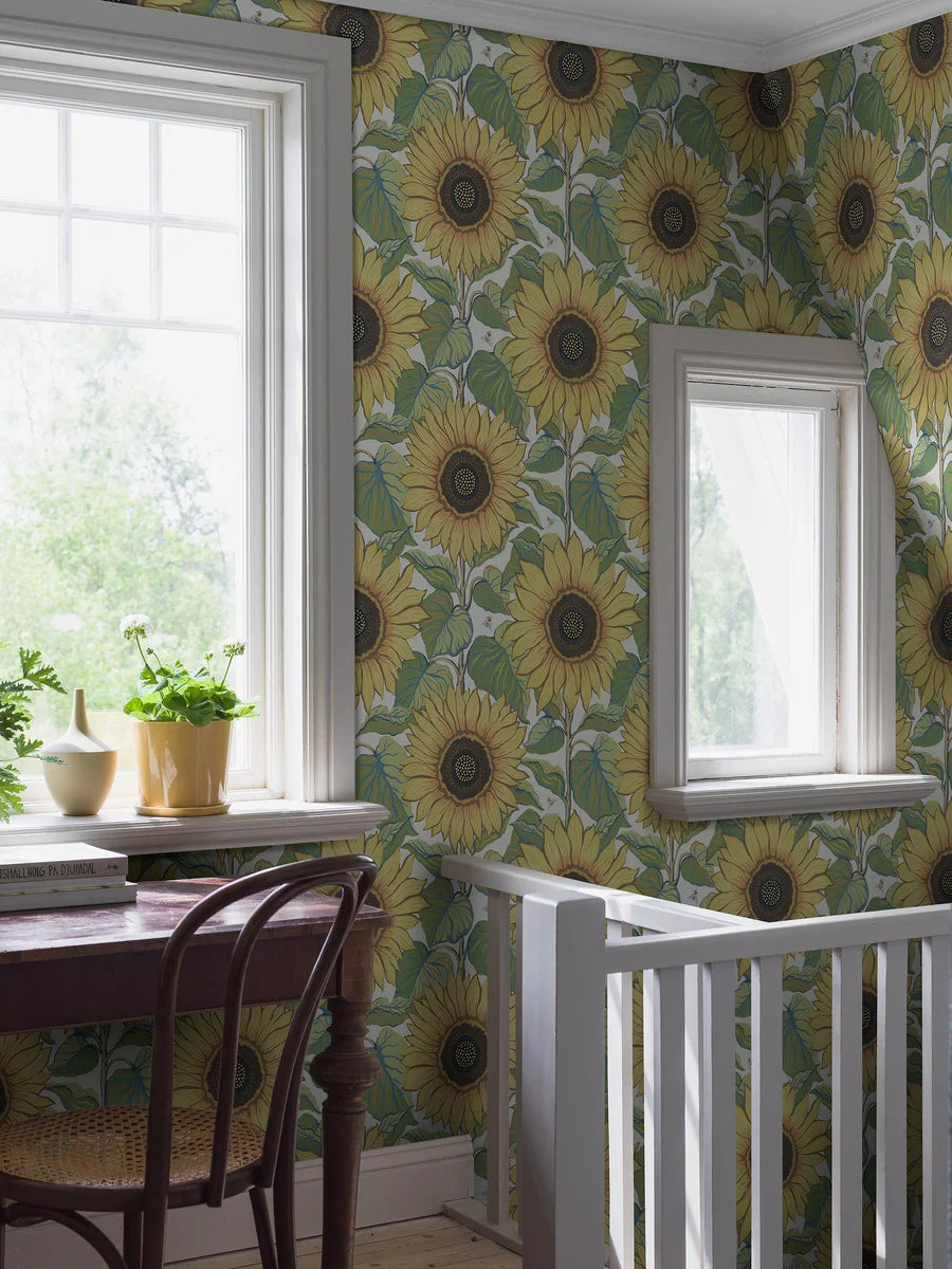 With a crisp white background and playful floral pattern in brilliant yellow, orange, green and blue tones, our Solrosor wallpaper, with a soft textile surface, cannot help but bring a bright and positive vibe to its surrounding space. 